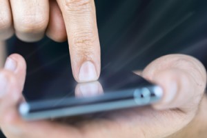 A worker taps the screen on his smartphone to access an app
