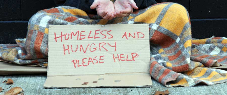 A homeless youth asks for donations with a sign saying "homeless and hungry - please help"