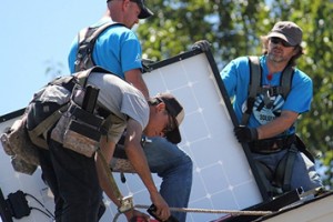 Electric workers install solar panels on a roof