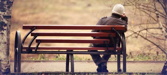 And elderly man sits alone on a park bench