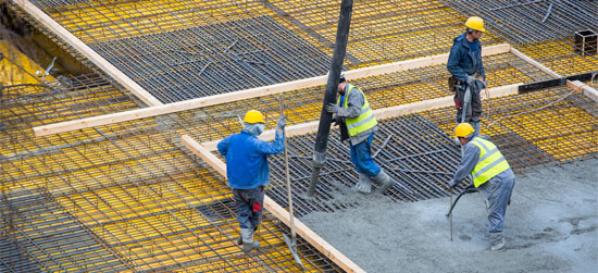 Construction workers pour concrete into a foundation of a building