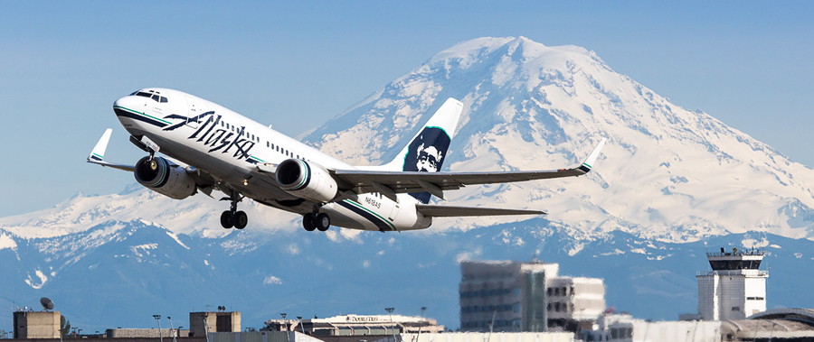 An Alaska Airline plane taking off from Sea-Tac International airport with Mt. Rainier in the background