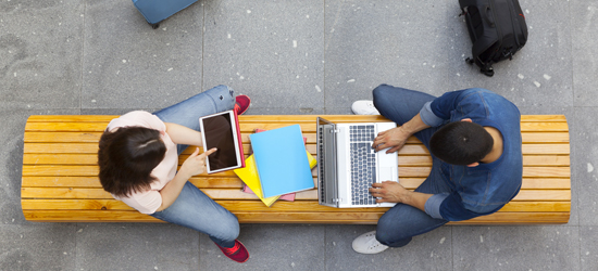 An overhead view of two technology workers sitting on park bench
