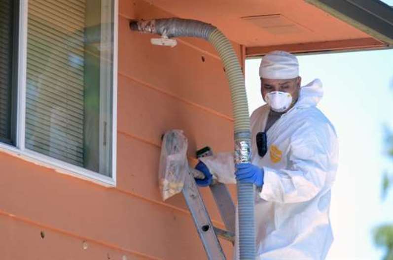 picture of worker blowing insulation into a home, funded by weatherization assistance program