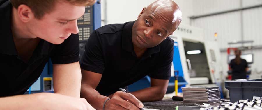 A supervisor trains a new employees on the company's processes