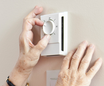 Hands adjusting thermostat on wall