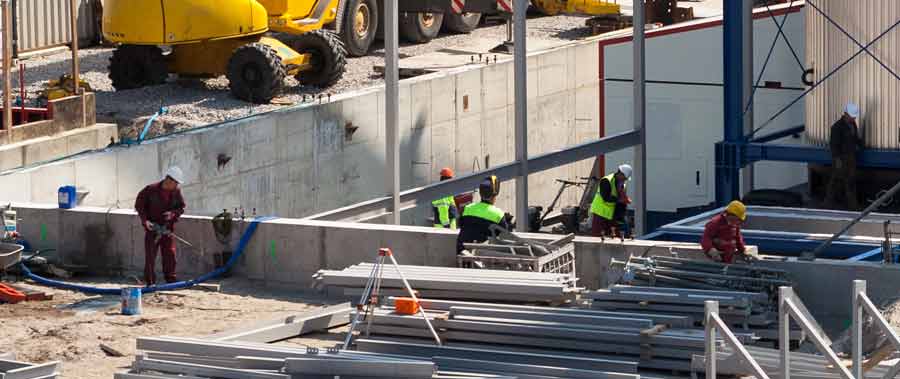 Workers begin to add steel beams to the foundation of a building