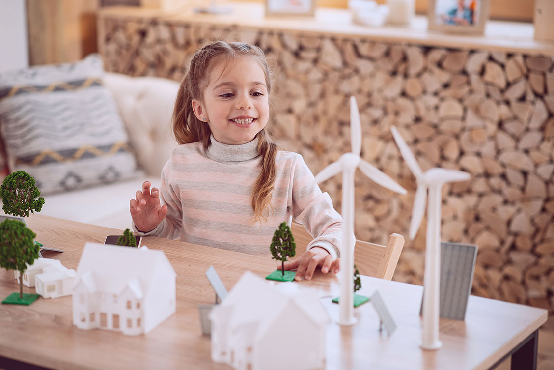 Young girl at table with miniature wind farm