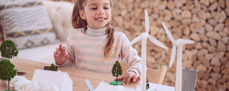 Young girl at table with miniature wind farm