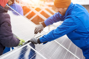 Worker with tools maintaining photovoltaic panels in winter. Engineers installing solar panels.