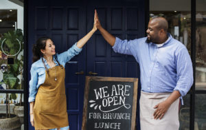 Small business owners high-fiving outside their establishment
