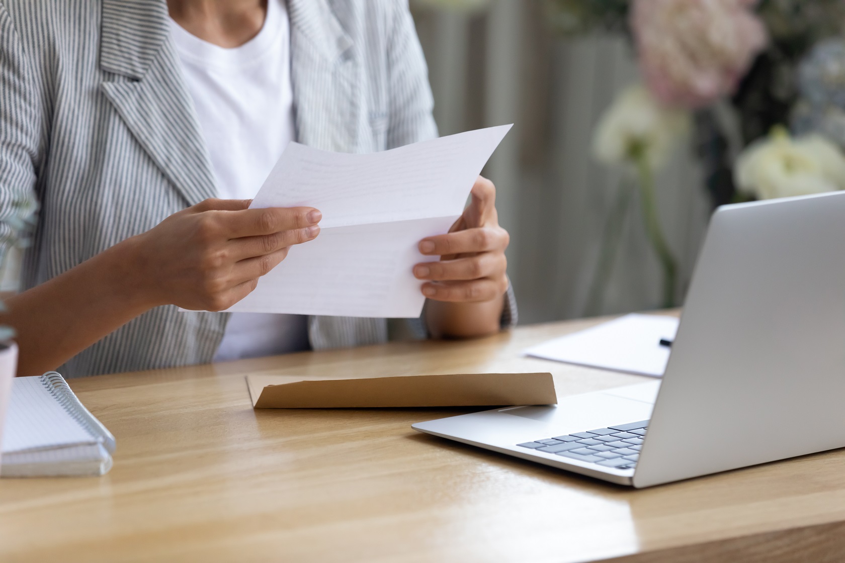 Young woman holding letter in hands reading information from bank