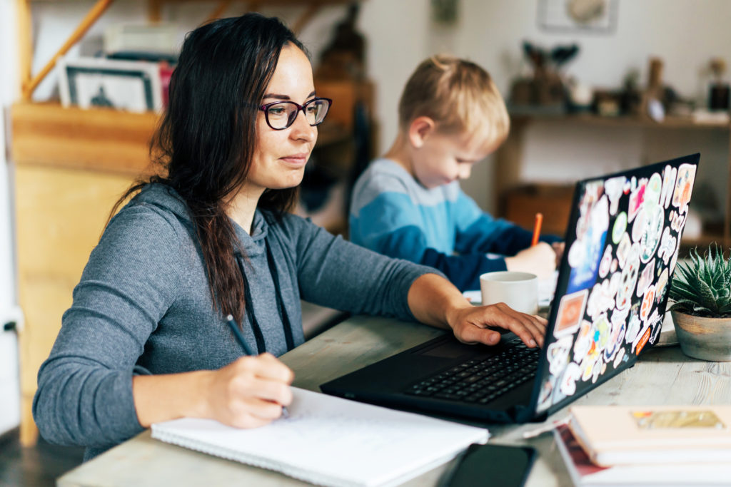 Woman working on laptop next to child