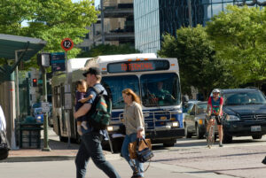 Photo of people walking on a downtown Bellevue street with a bus, bike rider and cars in the background