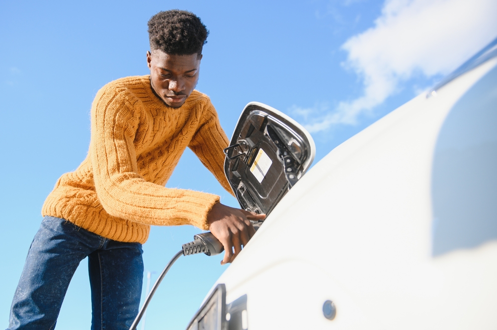 Person plugging in electric vehicle to charge