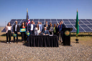 Photo of governor and supporters in front of solar panels as climate bill is signed into law