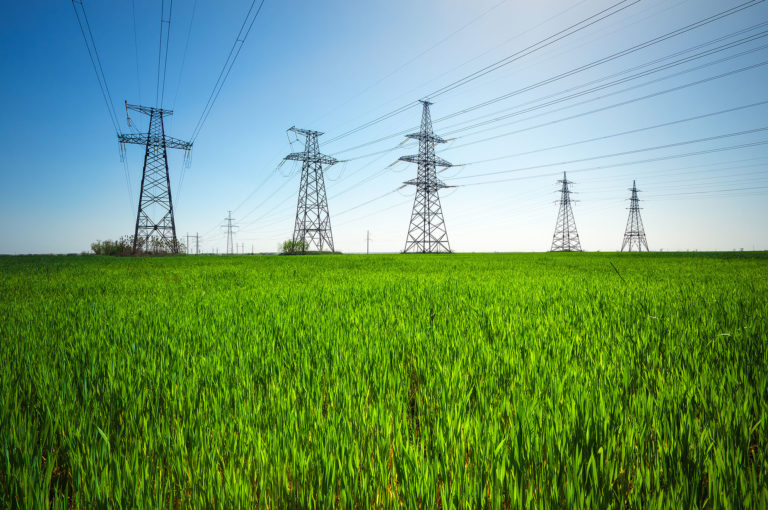 High voltage lines and power pylons in a green agricultural land