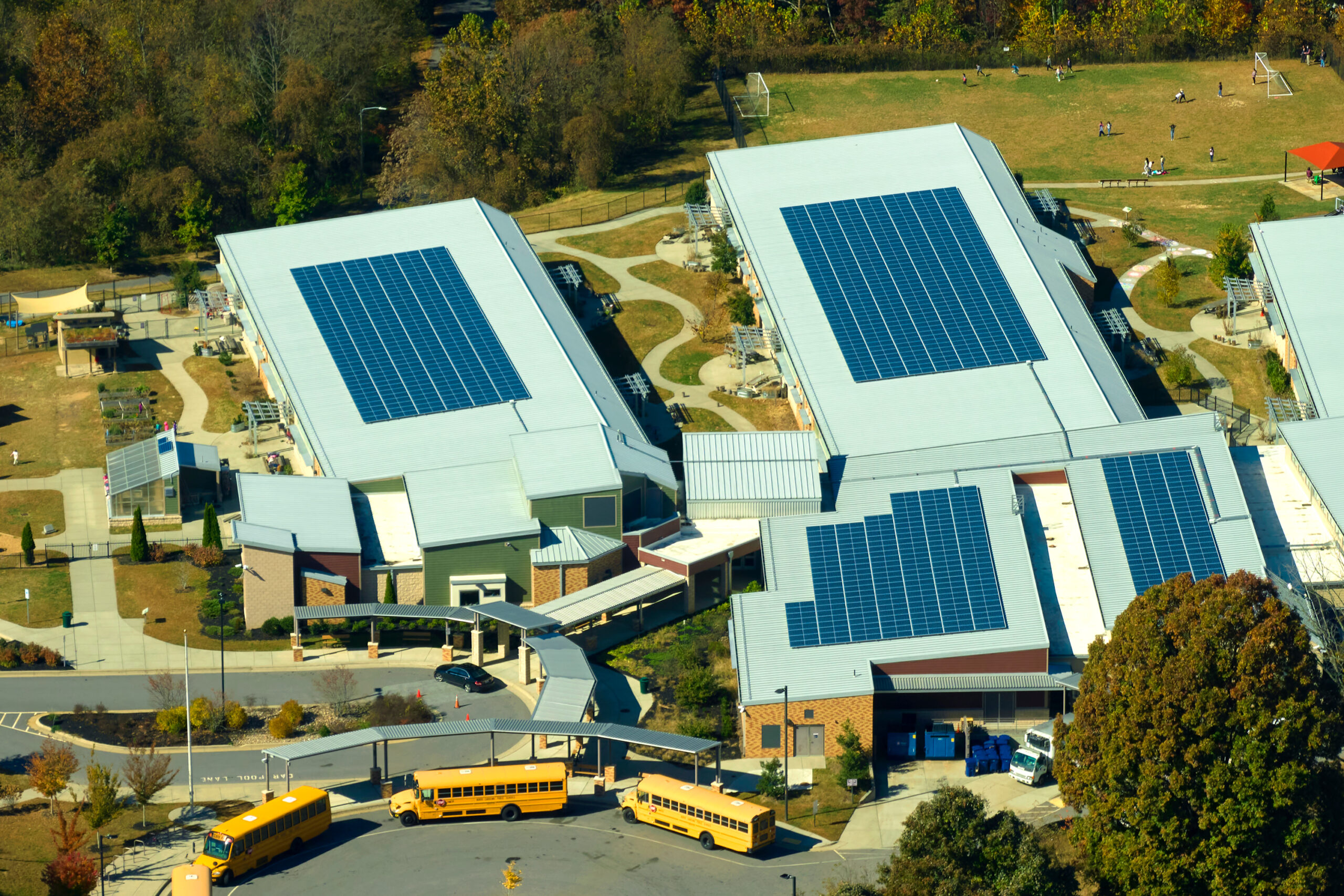 Roof of american school building covered with photovoltaic solar panels for production of electric energy. Renewable energy concept.