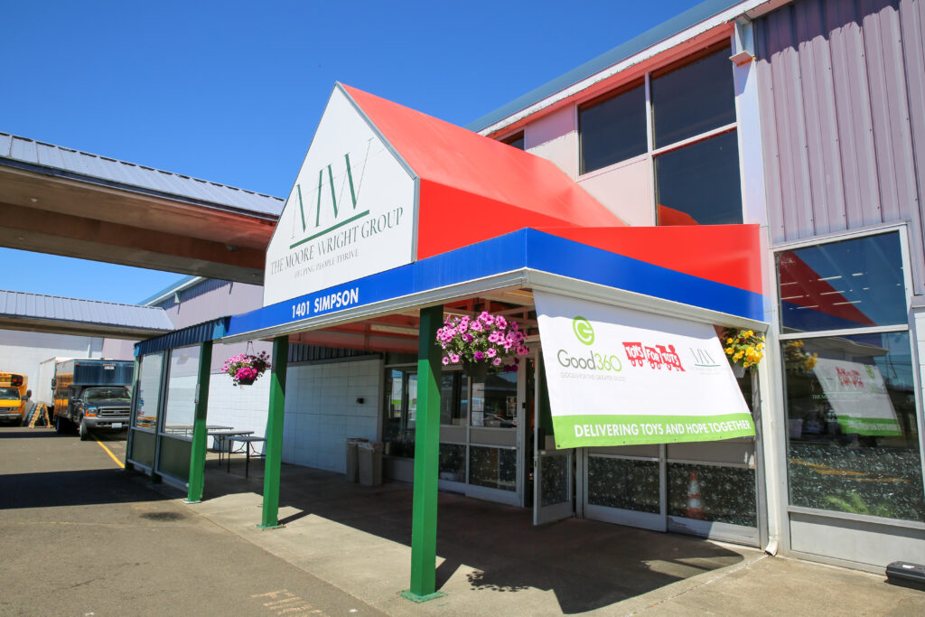 The entrance of The Moore Wright Group's warehouse location. The side's of the awning are red with a white front and the organization's logo in green.