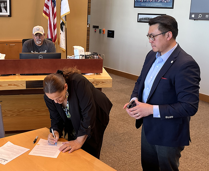 Council Member Marlin Fryberg, Jr. and Commerce Director Joe Nguyễn look on as Tulalip Tribes Chairwoman, Teri Gobin, signs the MOU.