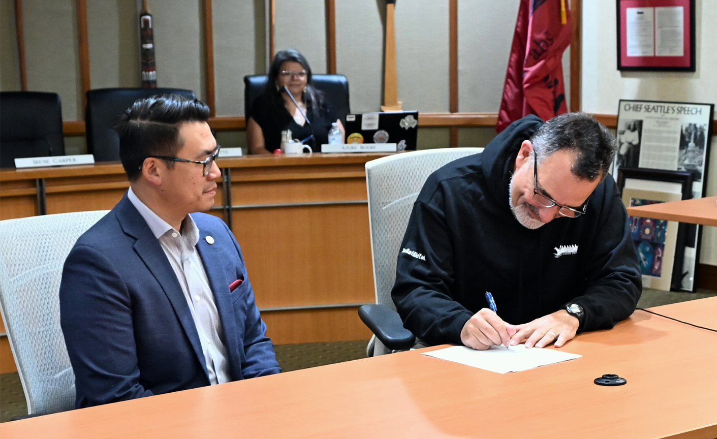 Suquamish Tribal Chair Leonard Forsman signs a new memorandum of understanding between the state Department of Commerce and the Tribe, while Commerce Director Joe Nguyen watches.