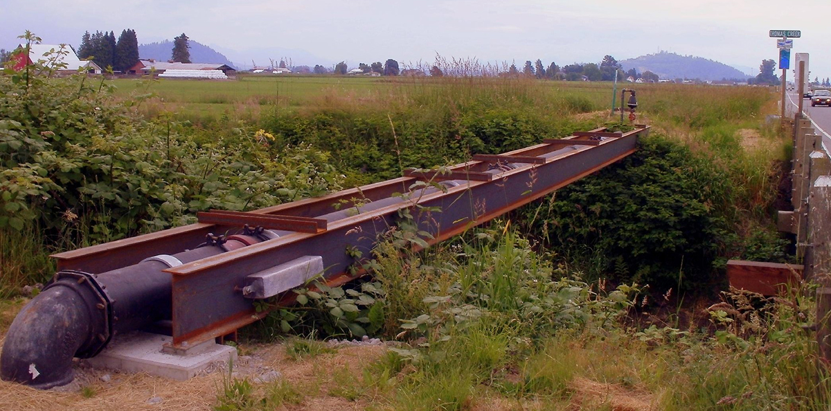 A sewer pipe runs parallel to a road.